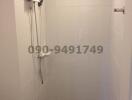 Modern white tiled bathroom with wall-mounted shower and electronic heater
