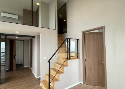 Modern loft apartment interior with wooden flooring and staircase leading to an upper level