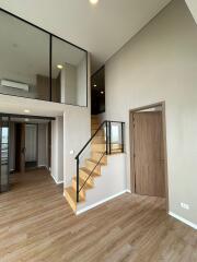 Modern loft apartment interior with wooden flooring and staircase leading to an upper level