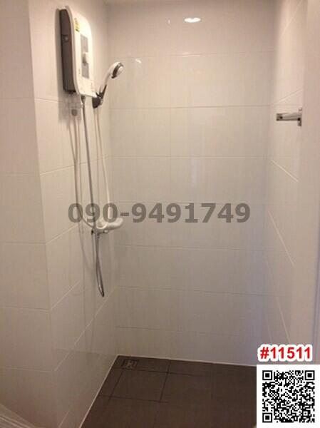 Modern white tiled bathroom with wall-mounted shower and digital thermostat