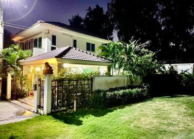 Night view of a well-lit, two-story suburban home with landscaped garden