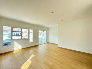 Spacious and brightly lit empty living room with hardwood floors and large windows