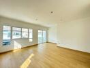 Spacious and brightly lit empty living room with hardwood floors and large windows