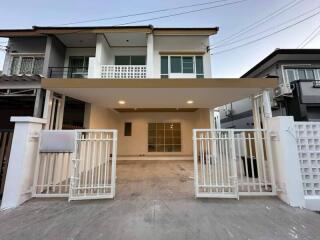 Modern two-story residential house with a spacious front porch and gated entrance