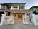 Modern two-story residential house with a spacious front porch and gated entrance