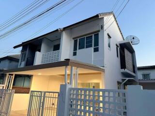Modern two-story residential building with balcony and secured gate