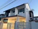 Modern two-story residential building with balcony and secured gate