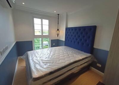 Spacious bedroom with large window and blue upholstered headboard