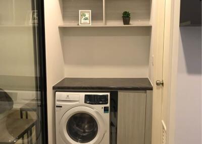Compact laundry area with modern washing machine and built-in shelves
