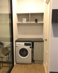 Compact laundry area with modern washing machine and built-in shelves