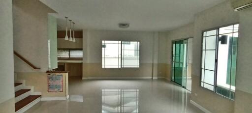 Spacious living room with large windows and kitchen access