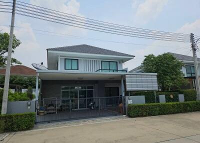 Exterior view of a modern two-story house with a gated entry