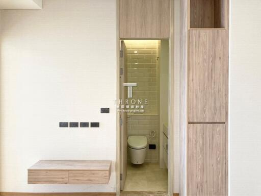 Modern entryway with sleek wooden features leading to a well-lit bathroom