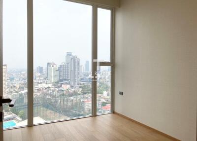 Spacious bedroom with large windows offering a panoramic city view