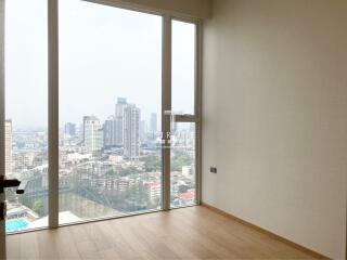 Spacious bedroom with large windows offering a panoramic city view