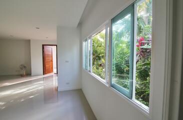 Spacious and well-lit living room with large windows overlooking lush greenery