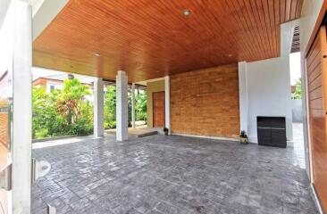 Spacious covered patio with wooden ceiling and textured stone floor