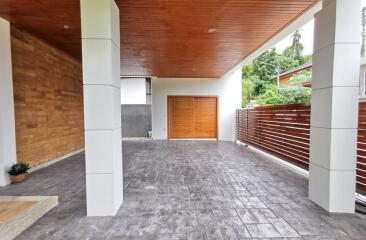 Spacious and elegant covered parking or entrance area with wood and brick details