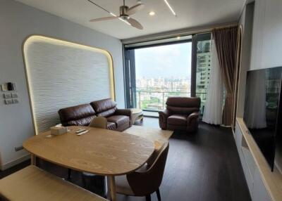 Modern living room with cityscape view featuring a brown leather sofa set and a wooden dining table