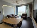 Modern living room with cityscape view featuring a brown leather sofa set and a wooden dining table