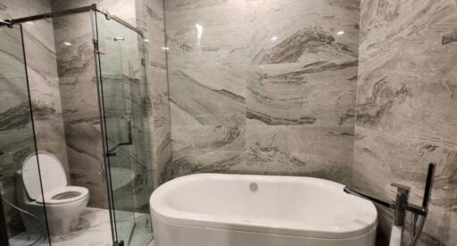 Luxurious bathroom with marble tiles featuring a bathtub and glass shower