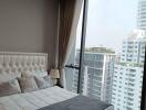 Modern bedroom interior with large window overlooking the city