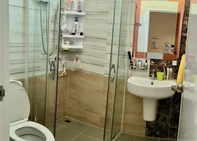 Modern bathroom with curved glass shower and beige tiles