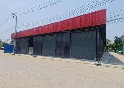 Exterior view of a commercial building with red facade and closed black roller shutters