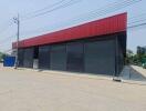 Exterior view of a commercial building with red facade and closed black roller shutters