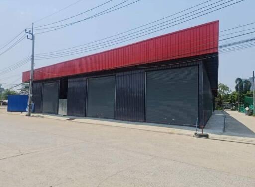 Exterior view of a commercial building with red facade and closed black roller shutters