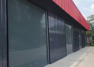 Exterior view of a modern industrial building with red and black facade and large shutter doors