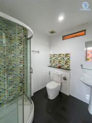 Modern bathroom with colorful tiled shower and white fixtures