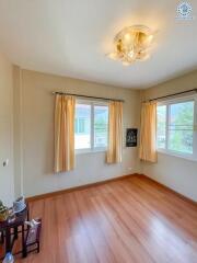 Spacious and well-lit bedroom with wooden flooring and large windows