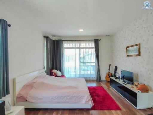 Spacious bedroom with large bed, entertainment system, and ample natural light