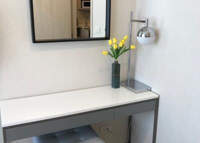 Modern bedroom with minimalist desk setup featuring a mirror and decorative flowers