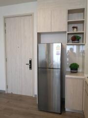 Modern kitchen interior with wooden cabinets and stainless steel refrigerator