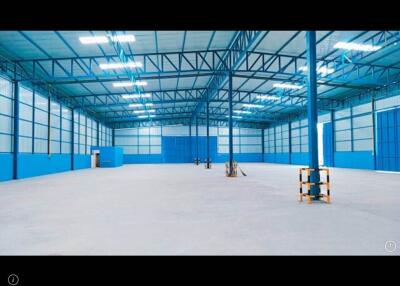 Spacious industrial warehouse interior with blue walls and high ceiling