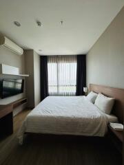 Modern bedroom with a large bed, wooden headboard, and city view