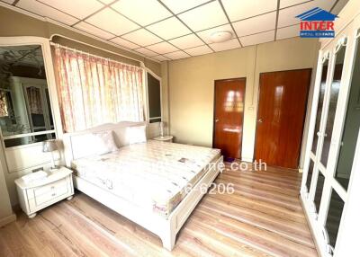 Spacious and well-lit bedroom with wooden flooring, large bed, and ample storage