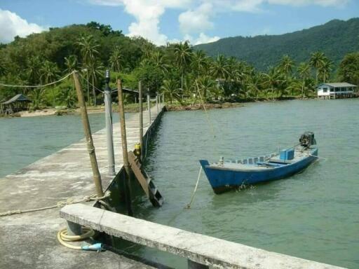 Tropical seaside with dock and boat overlooking lush green hills