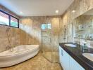 Luxurious bathroom with marble walls and floors, featuring a bathtub, glass shower, and modern vanity