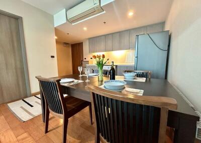 Modern dining area with view of the kitchen, featuring wooden dining table and contemporary design