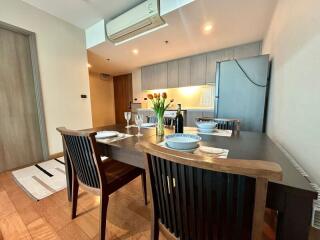 Modern dining area with view of the kitchen, featuring wooden dining table and contemporary design