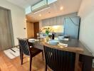 Modern dining area with view of the kitchen, featuring wooden dining table and contemporary design