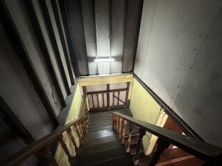 Dimly lit staircase inside a building with wooden railing