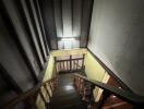 Dimly lit staircase inside a building with wooden railing