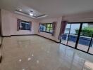 Spacious and well-lit living room with large windows and reflective tile flooring