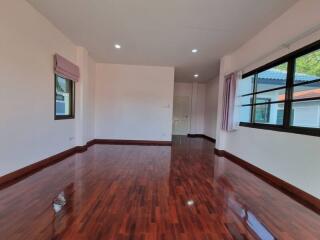 Spacious bedroom with wooden flooring and ample natural light