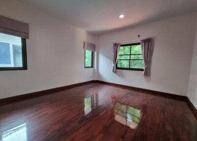 Spacious bedroom with glossy hardwood floors and ample natural light