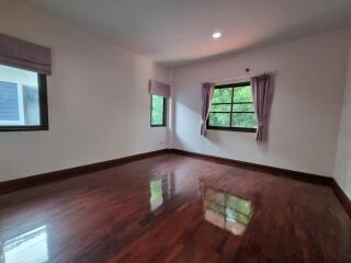 Spacious bedroom with glossy hardwood floors and ample natural light